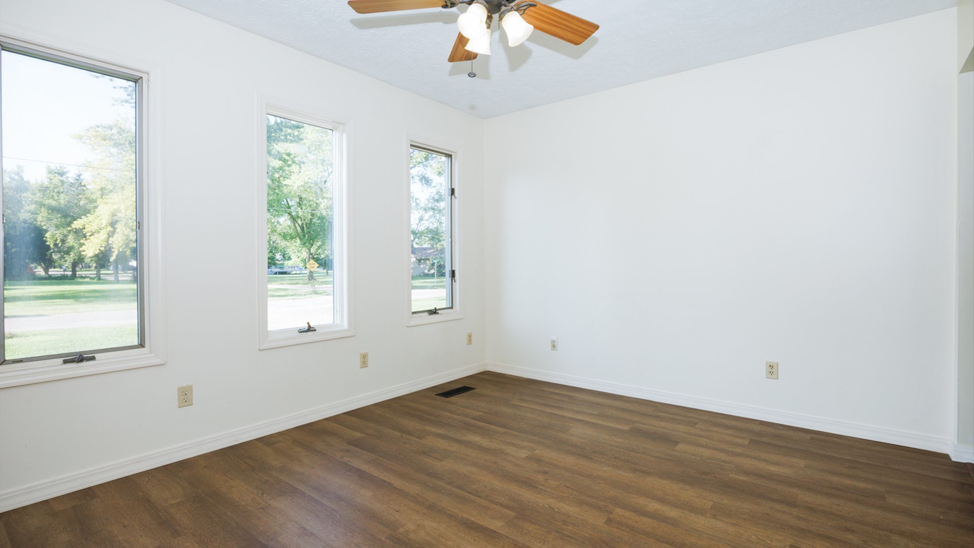 800 West Hamilton Street Atlanta, IL 61723 - Photo 11 of 44 an empty room with wooden floor chandelier fan and windows