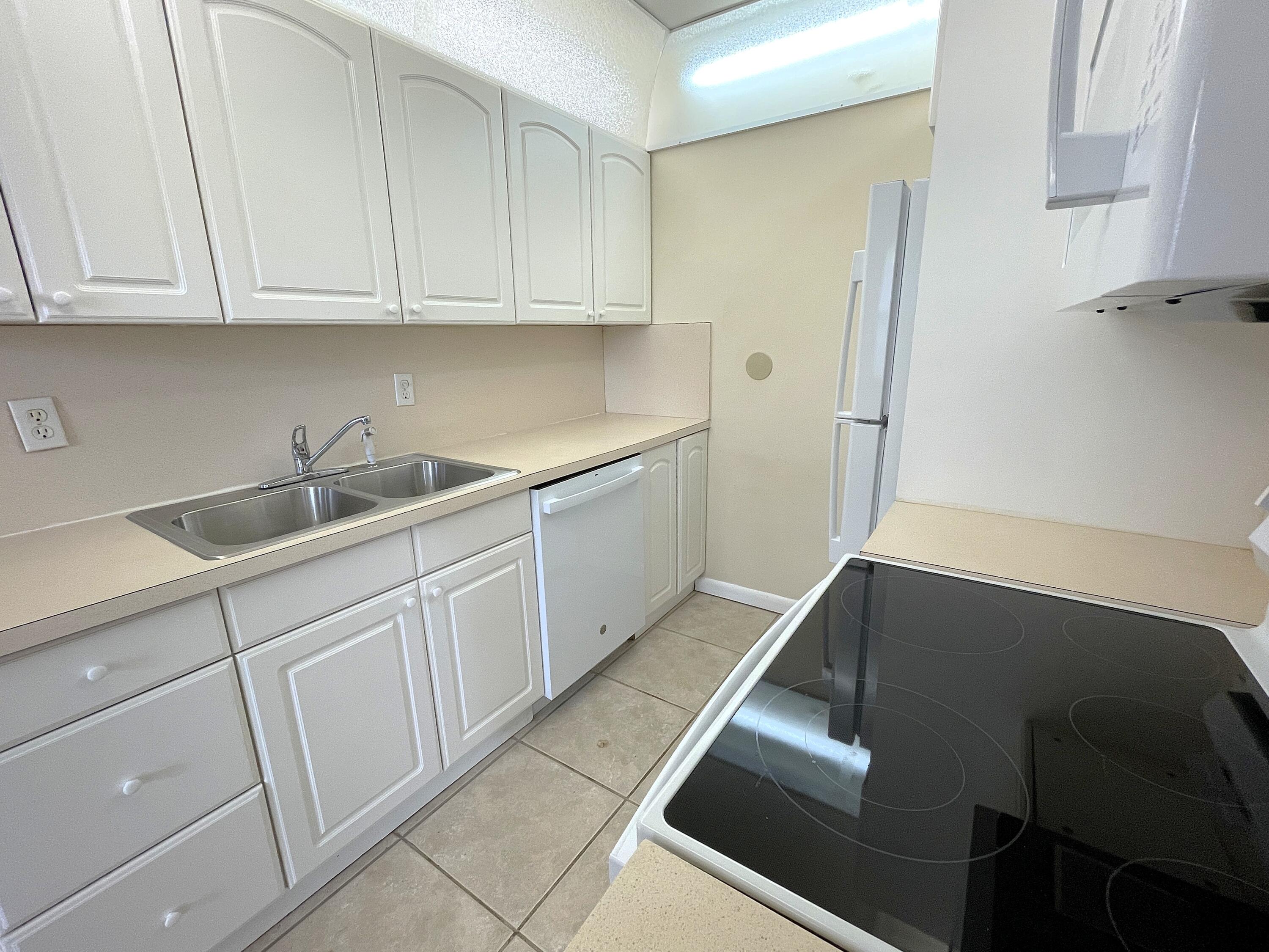 1020 Exeter, Unit 1020 Boca Raton, FL 33434 - Photo 6 of 29 a kitchen with white cabinets and a sink