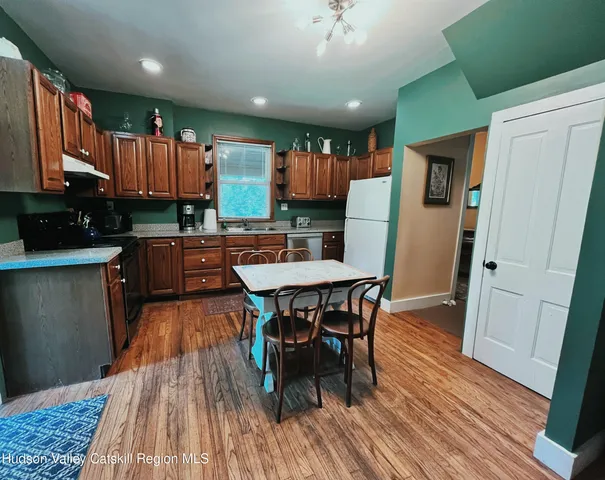 a kitchen with stainless steel appliances a dining table chairs and wooden floor