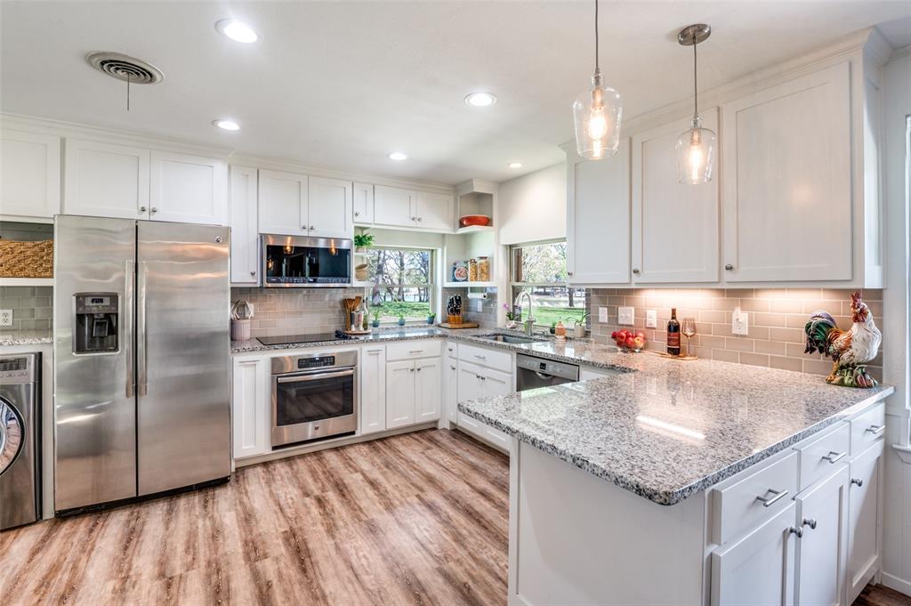 182 Huts Crossing Sadler, TX 76264 - Photo 10 of 40 a kitchen with kitchen island granite countertop a sink refrigerator and microwave