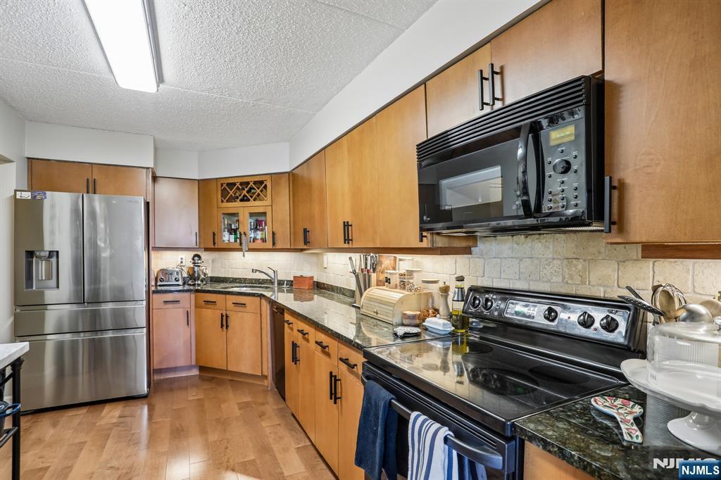 1077 River Road, Unit 303 Edgewater, NJ 07020 - Photo 12 of 27 a kitchen with stainless steel appliances granite countertop a stove top oven microwave and refrigerator