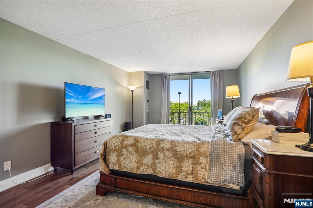 1077 River Road, Unit 303 Edgewater, NJ 07020 - Photo 15 of 27 a bedroom with a bed and dresser with wooden floor