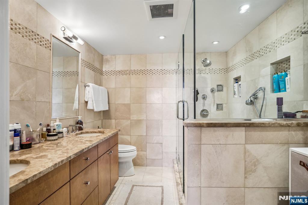 1077 River Road, Unit 303 Edgewater, NJ 07020 - Photo 17 of 27 a bathroom with a double vanity sink mirror and shower
