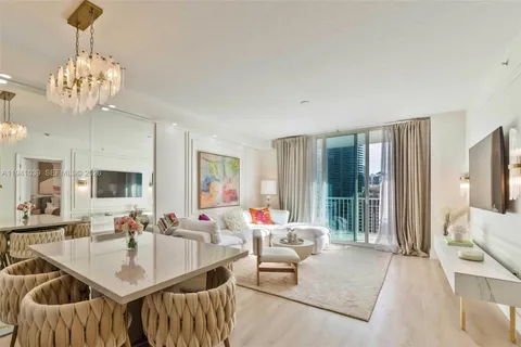 a living room with furniture dining table a large window and a chandelier