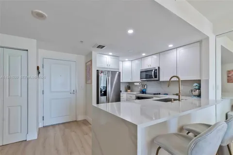 a kitchen with stainless steel appliances kitchen island granite countertop a refrigerator and a sink