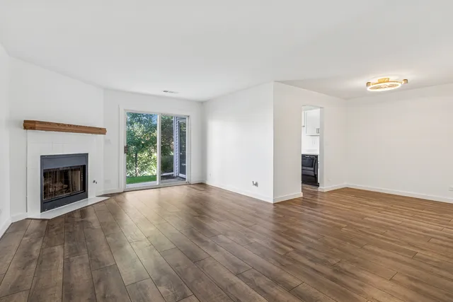 a view of empty room with wooden floor and fireplace