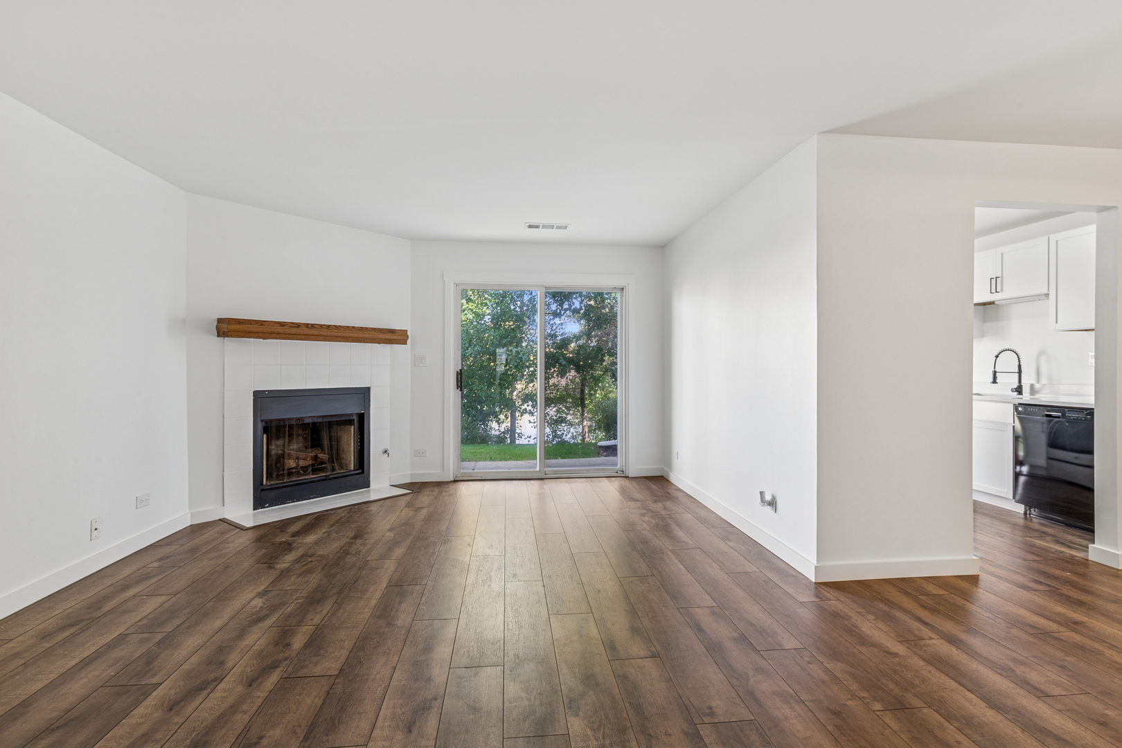 1240 Winfield Court, Unit 3 Roselle, IL 60172 - Photo 4 of 21 a view of an empty room with wooden floor fireplace and a window