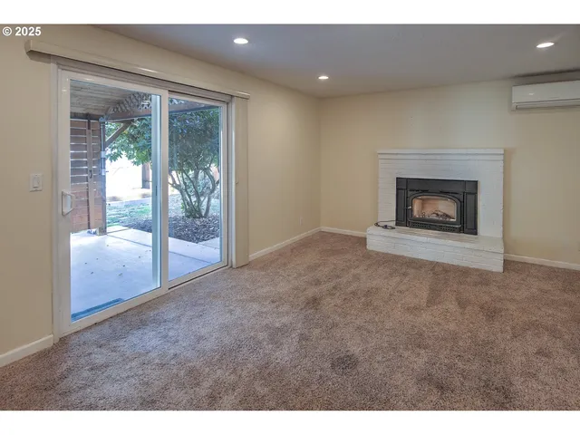 a view of an empty room with a fireplace and a window