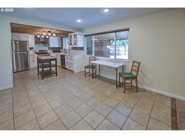 a open kitchen with stainless steel appliances kitchen island granite countertop a refrigerator and a sink