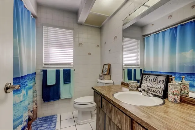 a bathroom with a granite countertop sink toilet and mirror
