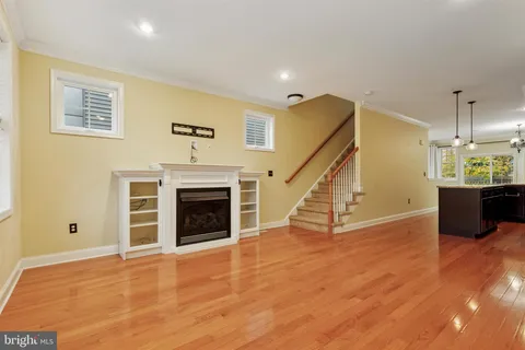 a view of an empty room with wooden floor fireplace and a window