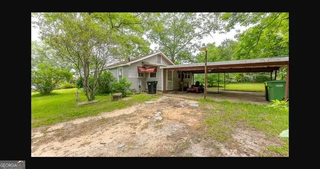 a view of house with backyard outdoor seating and trees in the background