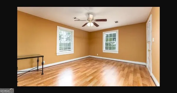 a view of an empty room with window and wooden floor