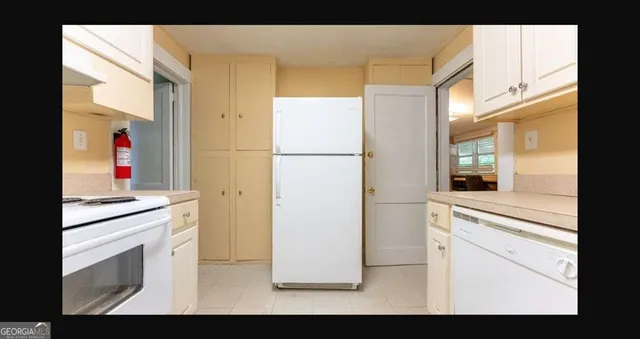 a kitchen with a refrigerator and white cabinets