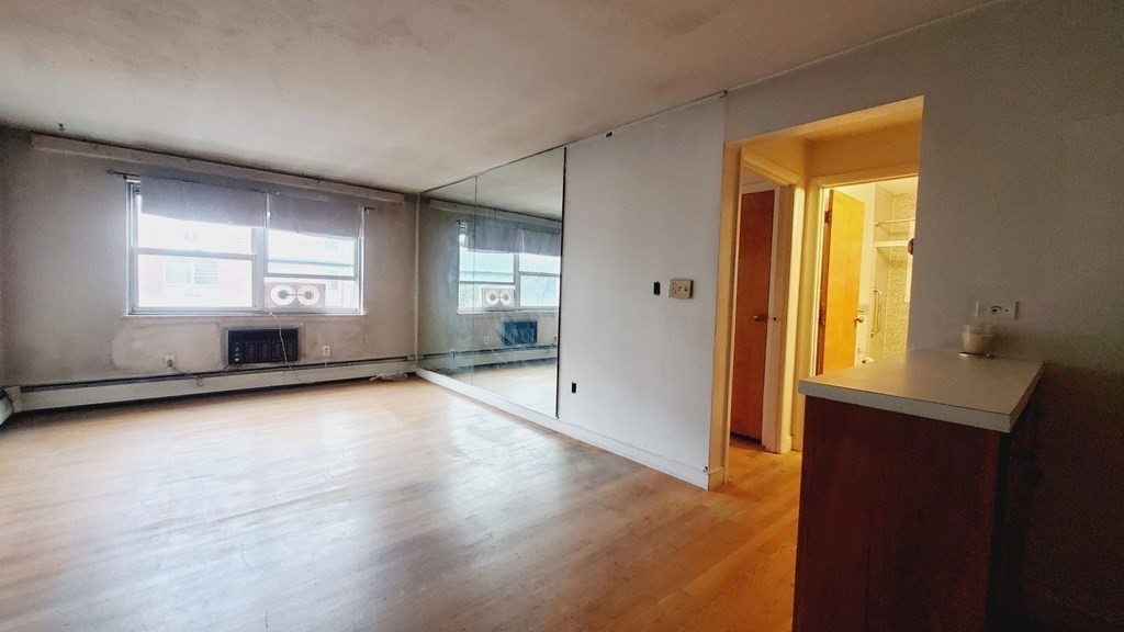 a view of empty room with wooden floor and fan