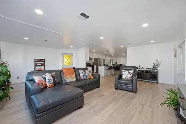 a living room with furniture kitchen view and a wooden floor