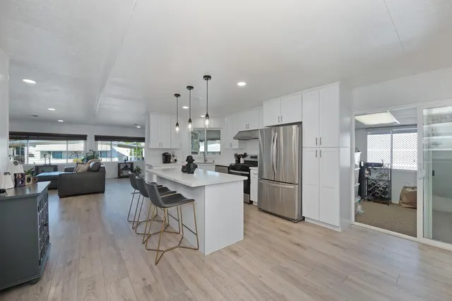 a kitchen with stainless steel appliances kitchen island granite countertop a sink refrigerator and cabinets