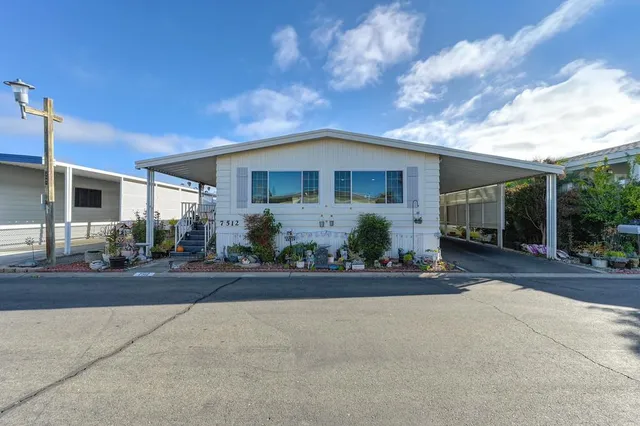 a front view of a house with a yard and potted plants