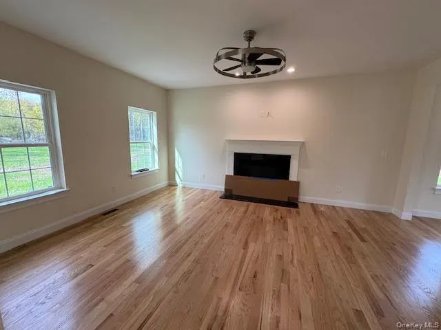 a view of empty room with wooden floor and window