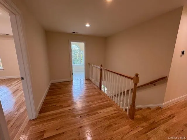 a view of a hallway with wooden floor and staircase