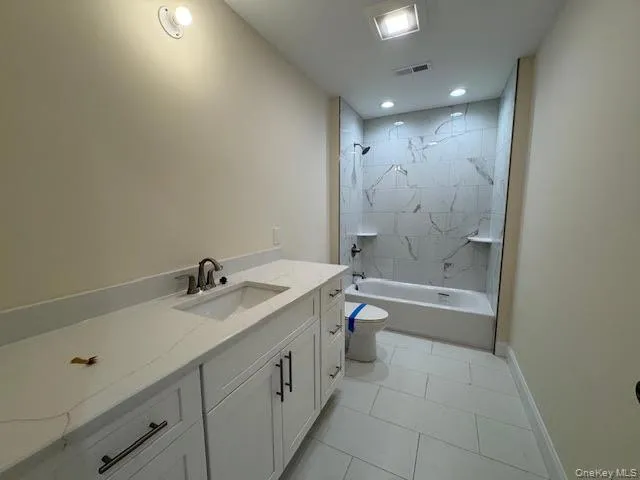 a bathroom with a granite countertop sink a toilet and bathtub
