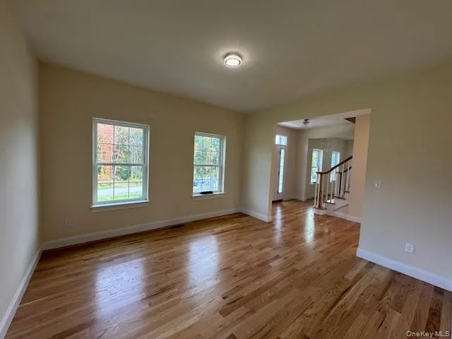 a view of empty room with wooden floor and fan