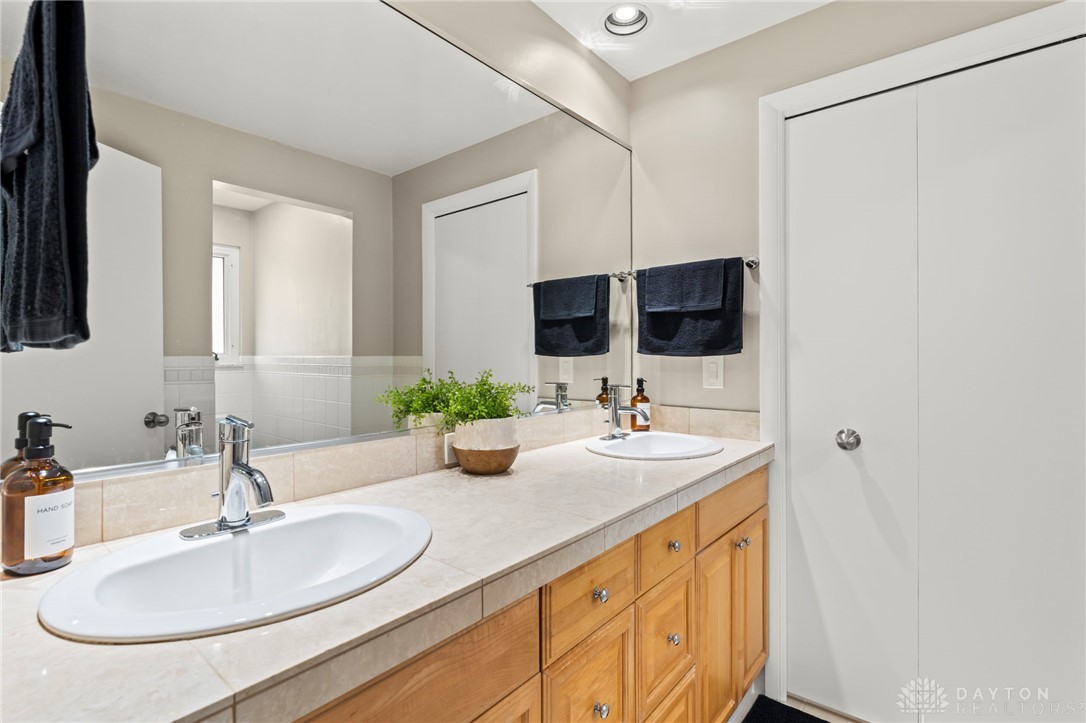 2247 East Whipp Road Dayton, OH 45440 - Photo 27 of 52 This bathroom features a double vanity with tile countertops and a full-width mirror.