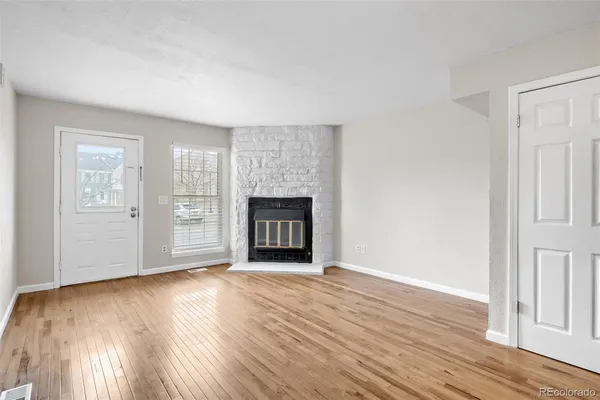 an empty room with wooden floor fireplace and windows