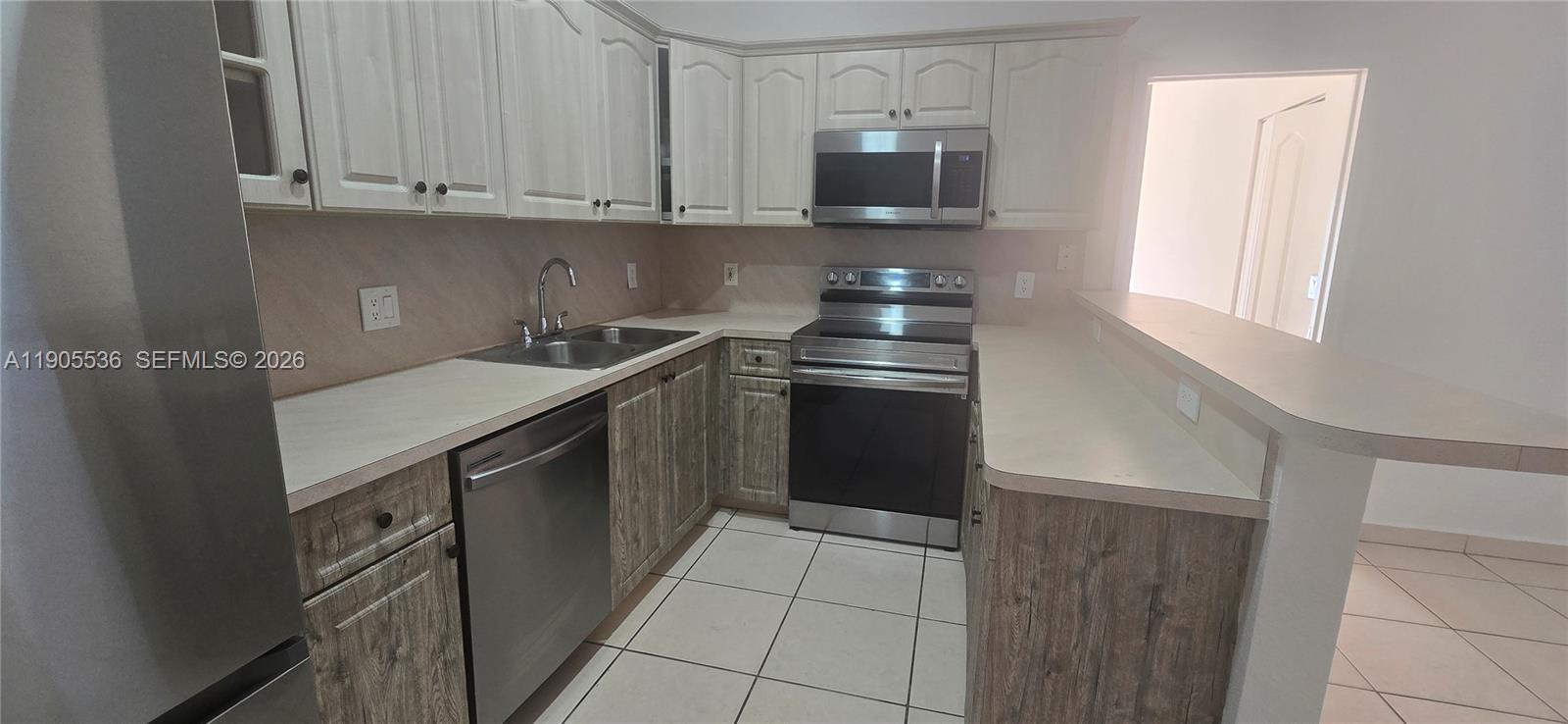7510 Northwest 175th Street, Unit 7510 Hialeah, FL 33015 - Photo 13 of 14 a kitchen with stainless steel appliances granite countertop a sink and a microwave