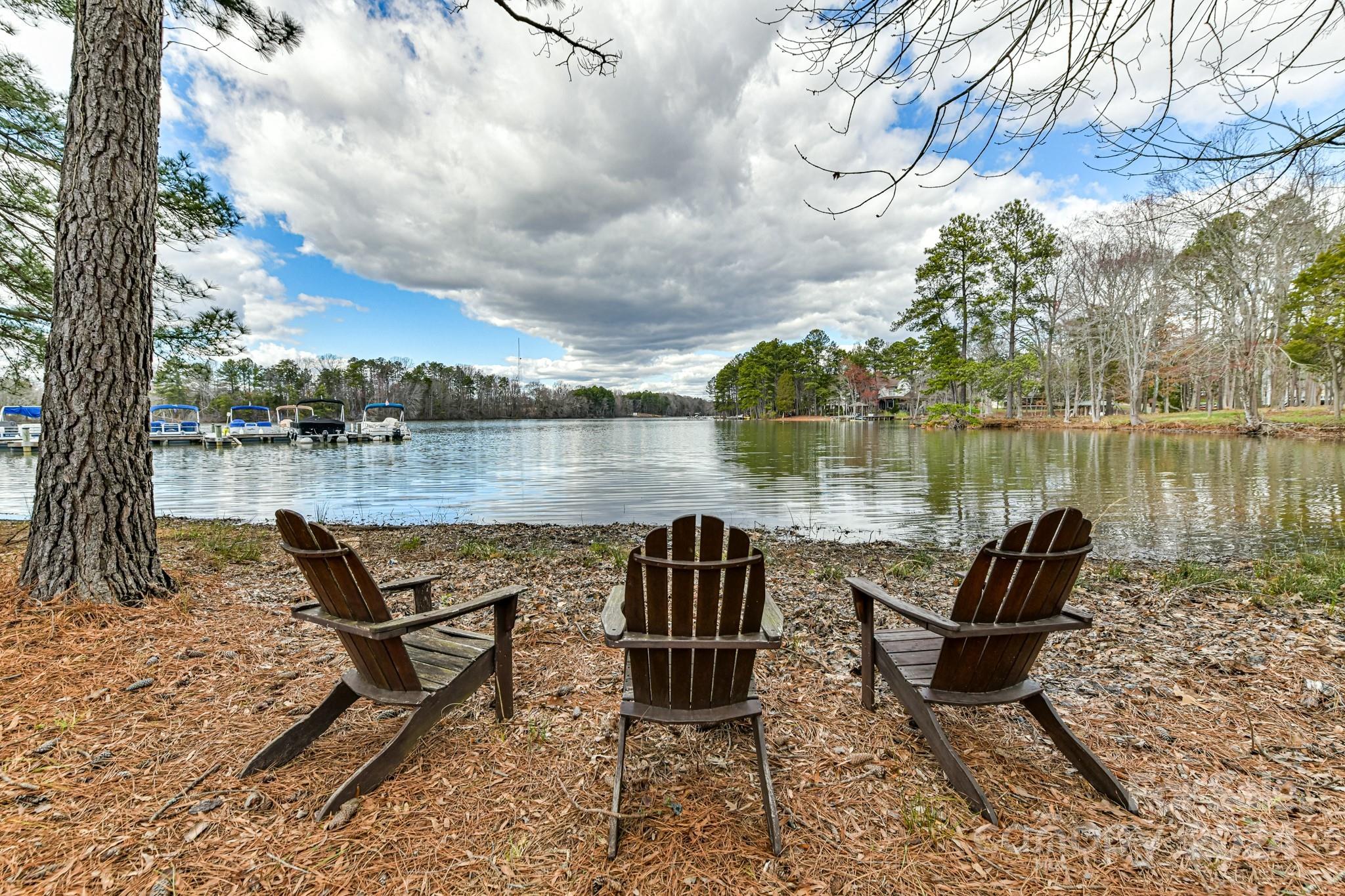 111 Poppy Field Lane Davidson, NC 28115 - Photo 23 of 28 a lake view with table and chairs next to a yard with wooden fence