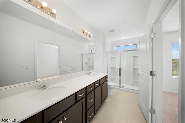 a spacious bathroom with a double vanity sink a mirror and a shower
