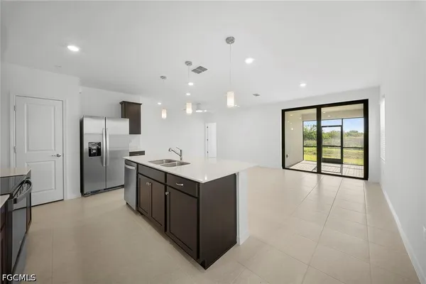 a kitchen with stainless steel appliances kitchen island granite countertop a refrigerator and a sink