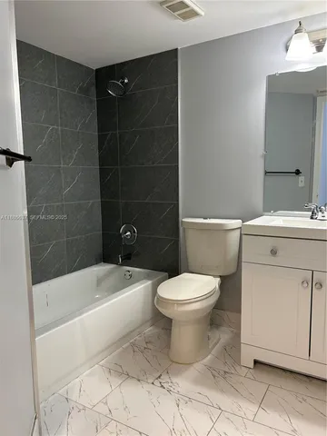 a bathroom with a toilet a sink a mirror and bathtub