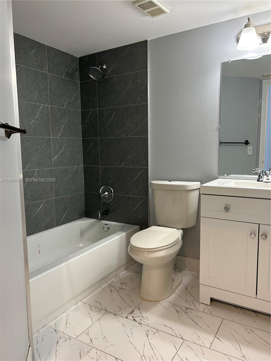 8801 Wiles Road, Unit 306 Coral Springs, FL 33067 - Photo 5 of 20 a bathroom with a toilet a sink a mirror and bathtub