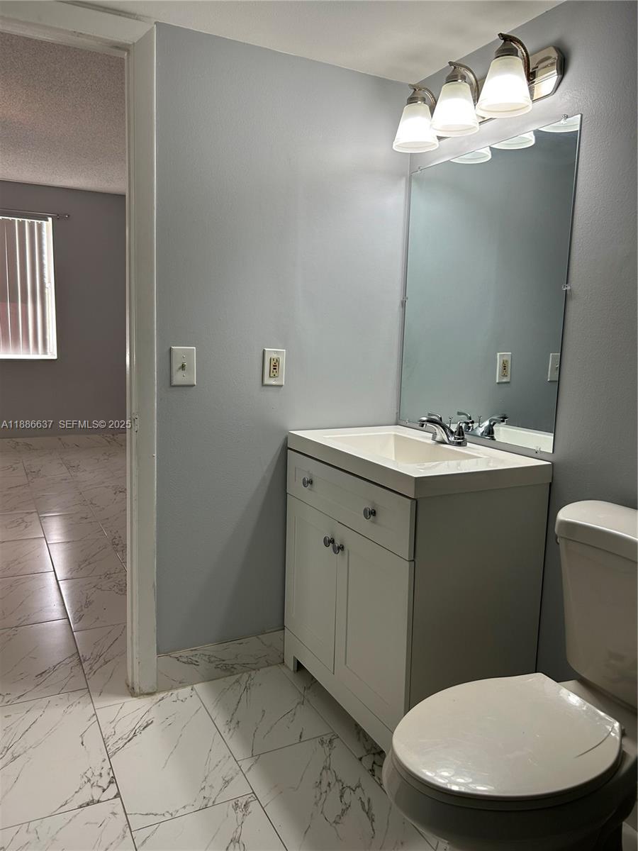 8801 Wiles Road, Unit 306 Coral Springs, FL 33067 - Photo 10 of 20 a bathroom with a sink a toilet and mirror