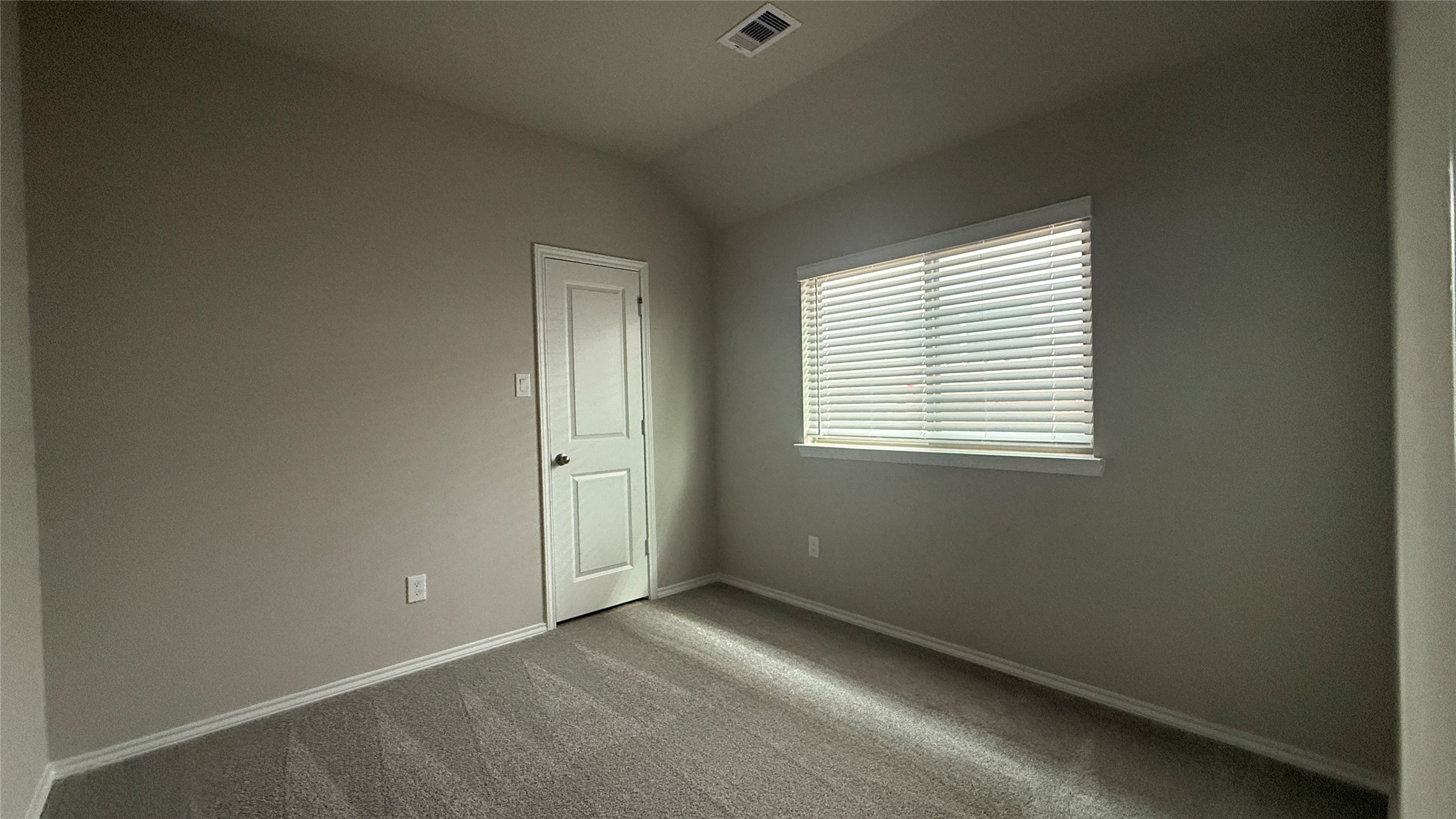 31961 Retama Rnch Drive Spring, TX 77386 - Photo 16 of 25 This photo shows a small, carpeted room with neutral-colored walls and a window with blinds, allowing natural light to enter. It features a single door, likely leading to a closet or hallway.