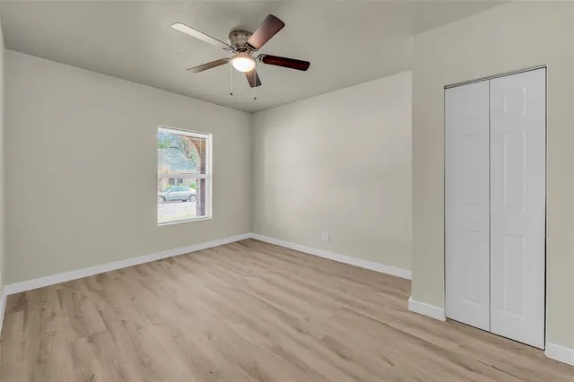 an empty room with wooden floor ceiling fan and windows