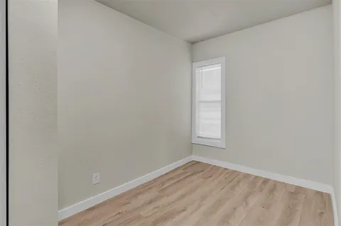 a view of an empty room and wooden floor and a window