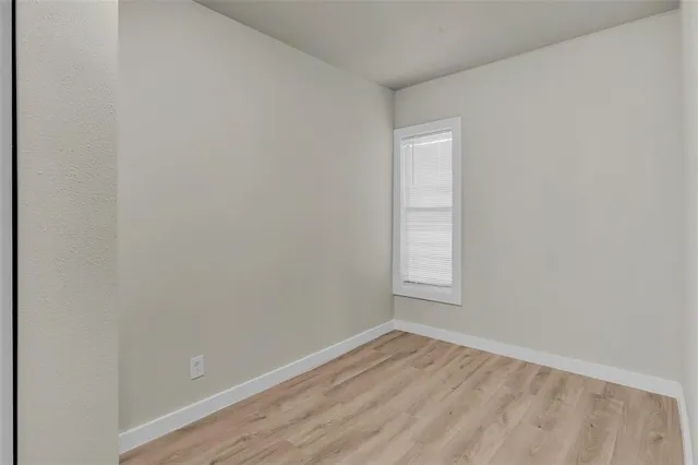 a view of an empty room and wooden floor and a window