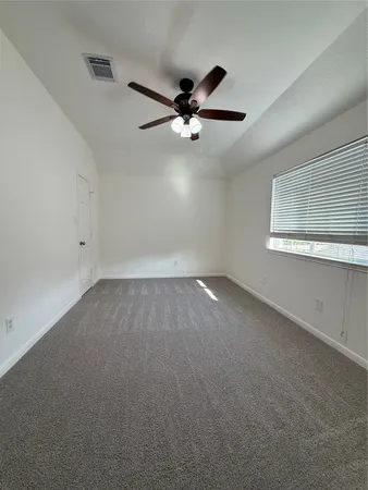 an empty room with a window and ceiling fan