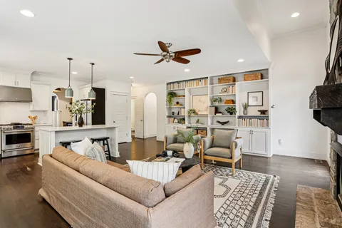 a living room with furniture kitchen view and a wooden floor