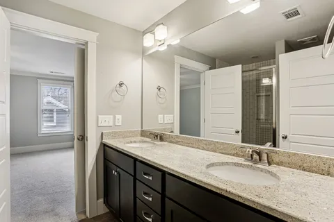 a bathroom with a granite countertop double vanity sink and mirror
