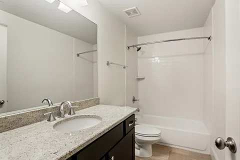 a bathroom with a granite countertop sink toilet and shower