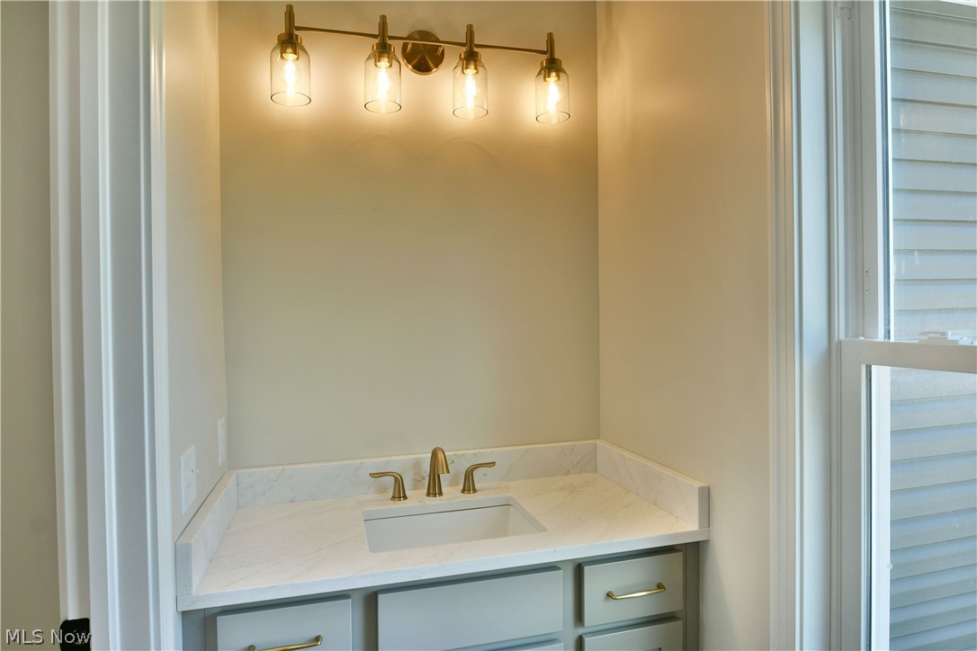 4780 State Rte 5 Cortland, OH 44410 - Photo 27 of 50 Built-in vanity with a rectangular undermount sink, light-toned countertop, and brass-finish faucet