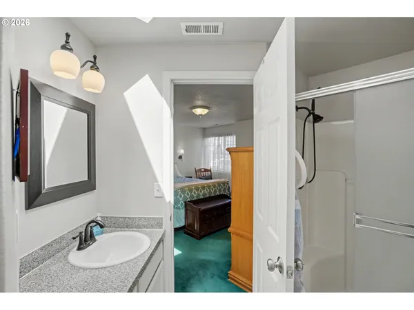a en suite bathroom with a granite countertop sink mirror and a shower