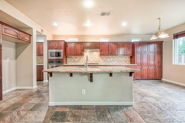a view of kitchen with stainless steel appliances granite countertop a stove and a sink