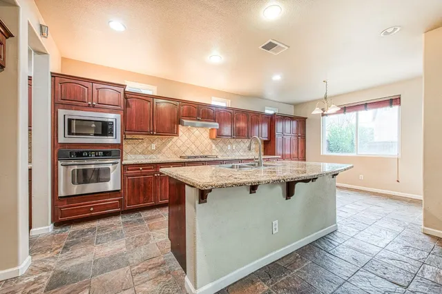 a kitchen with stainless steel appliances granite countertop a stove a sink and a microwave