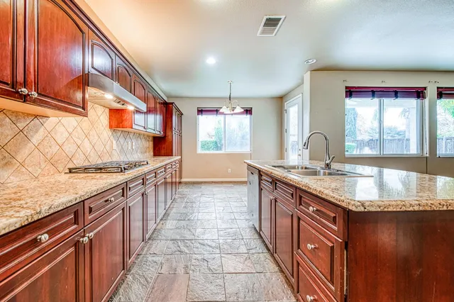 a kitchen with stainless steel appliances granite countertop a sink and a stove