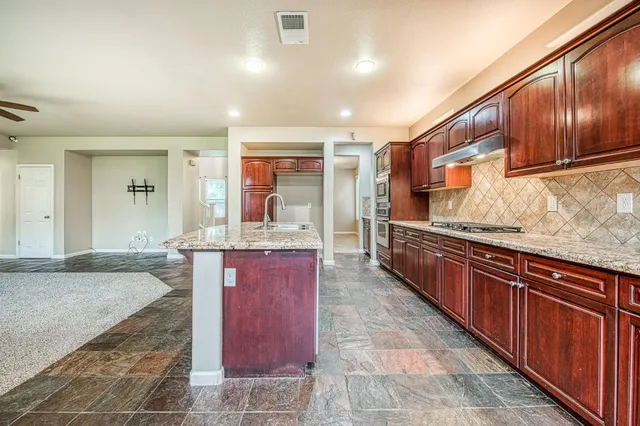 a large kitchen with kitchen island granite countertop wooden cabinets a granite counter tops and a view of living room