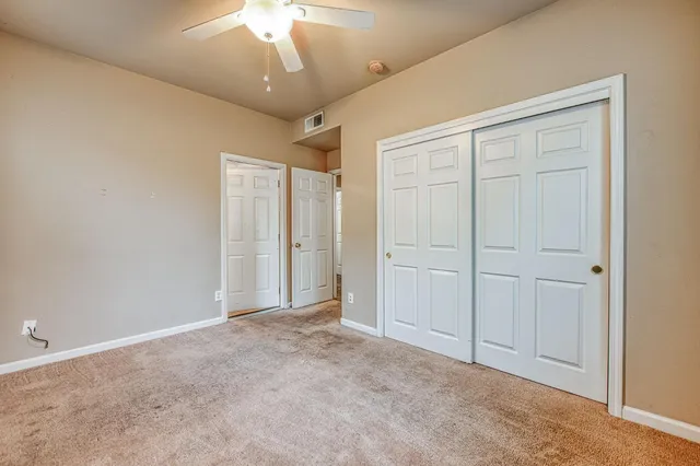a view of an empty room and chandelier fan